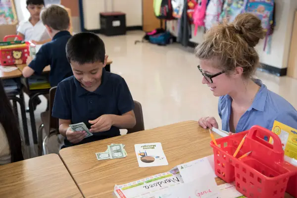 Junior Achievement Volunteer Helping Student With Financial Literacy Activities